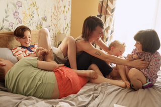 Famille allongée ensemble sur un lit – Assurance personnalisée AXA pour chaque foyer