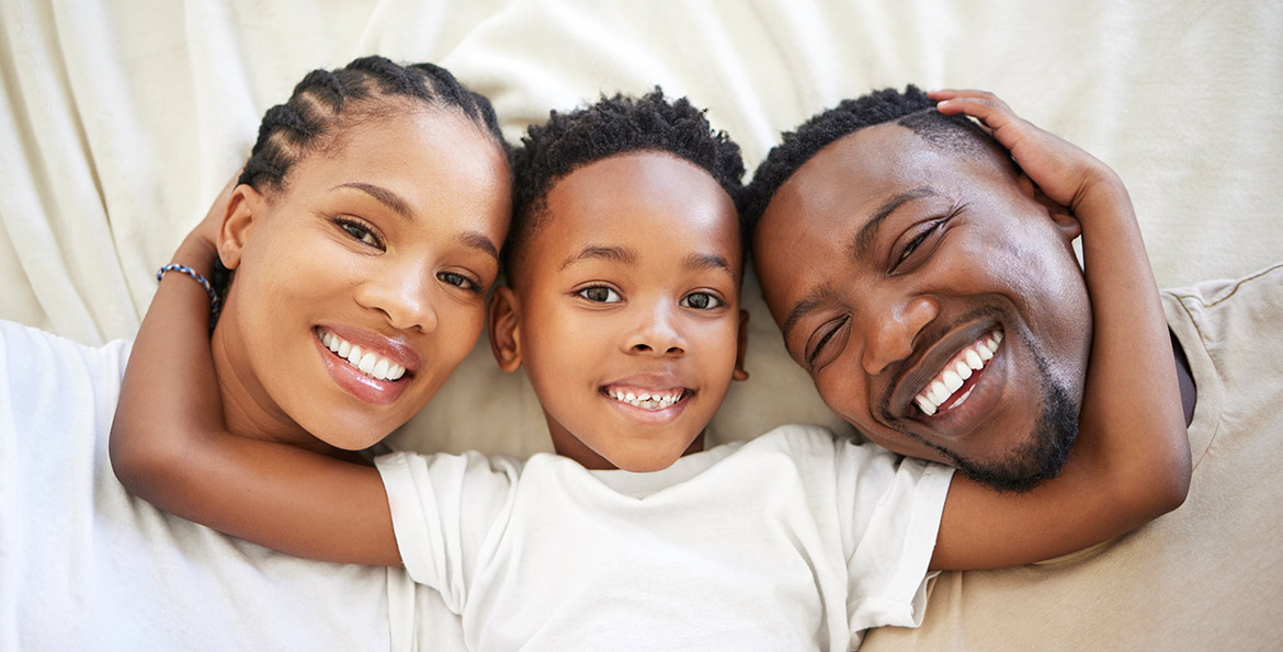 Famille souriante dans un canapé – Prévoyance AXA pour sécuriser les revenus face aux imprévus