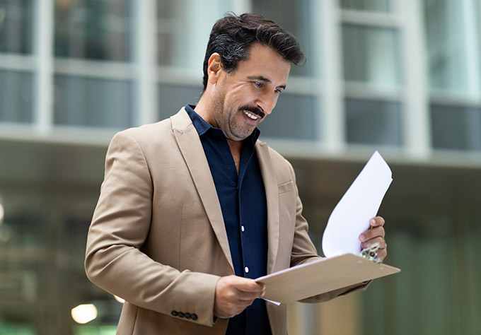 Homme souriant consultant un formulaire – Mutuelle santé adaptée à vos bes