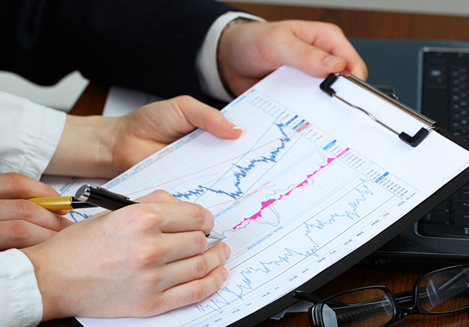 Main analysant un graphique boursier – Investir en bourse avec le PEA AXA