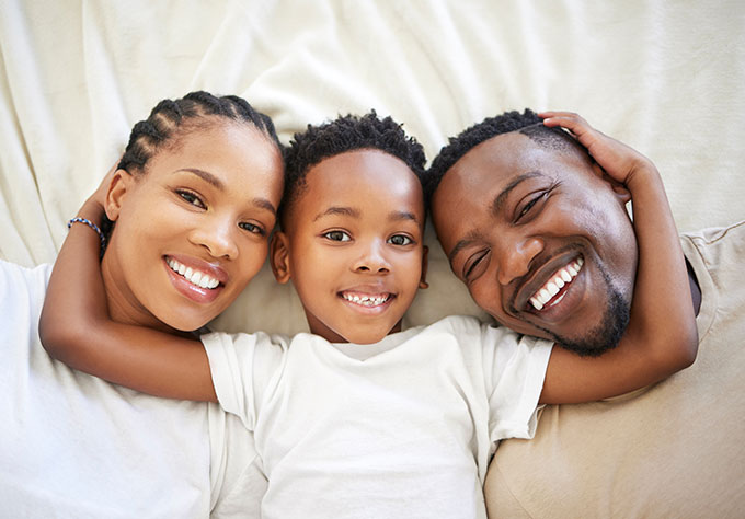 Famille souriante dans un canapé – Prévoyance AXA pour sécuriser les revenus face aux imprévus